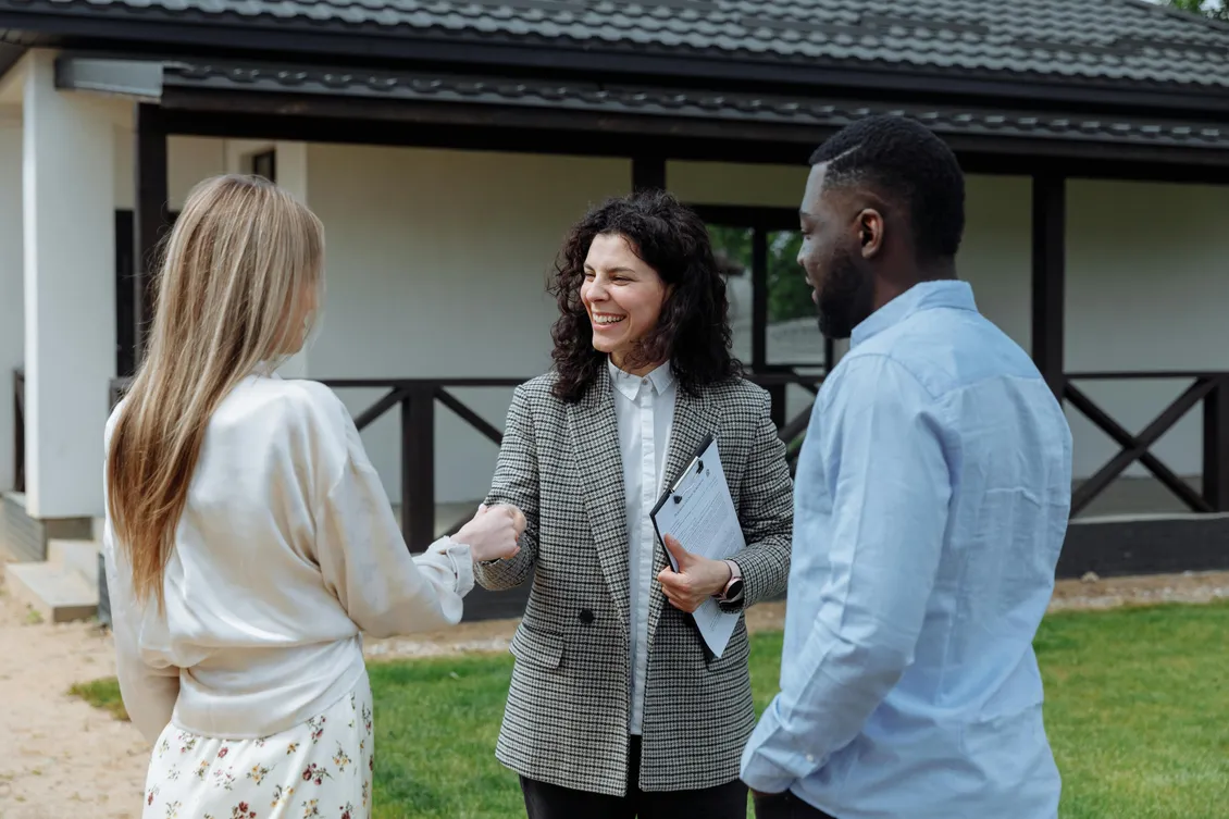 Two real estate agents greeting a client outside a home