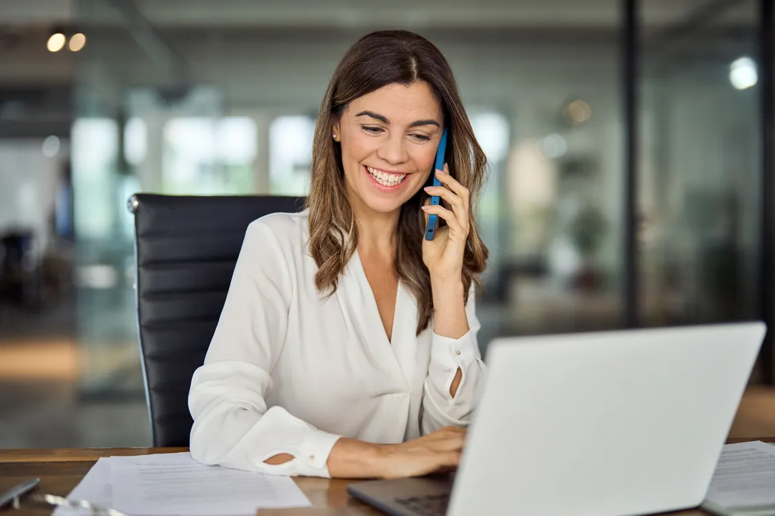 A real estate agent on the phone at her laptop, smiling