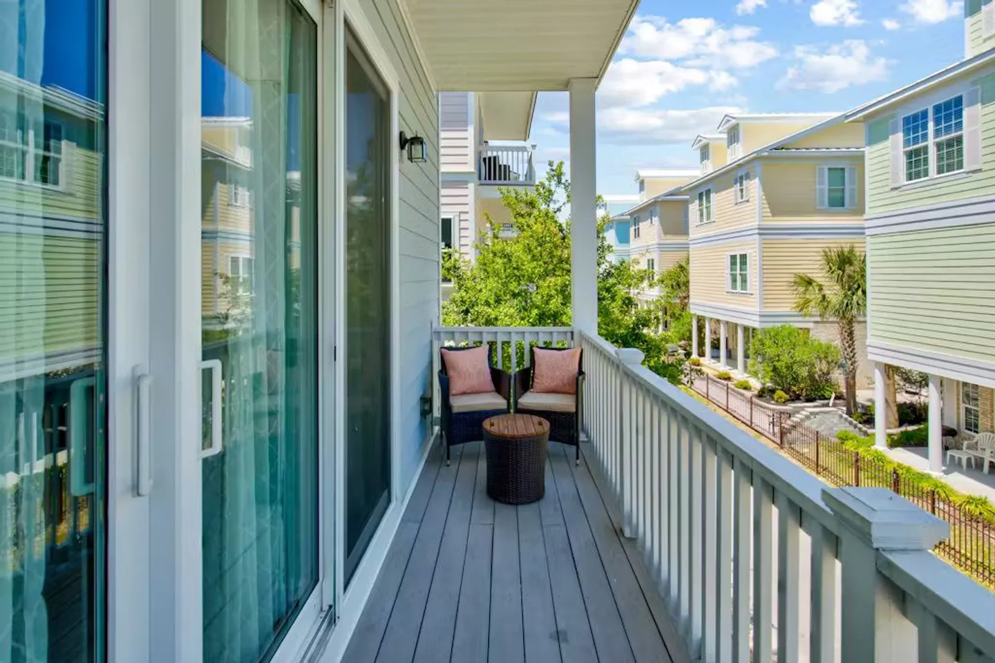 A covered balcony with two armchairs and a small round table overlooking a neighborhood of colorful homes.