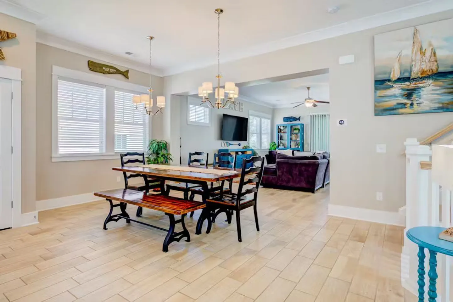 Dining area with a wooden table, bench, and chairs, opening into an adjacent living room.