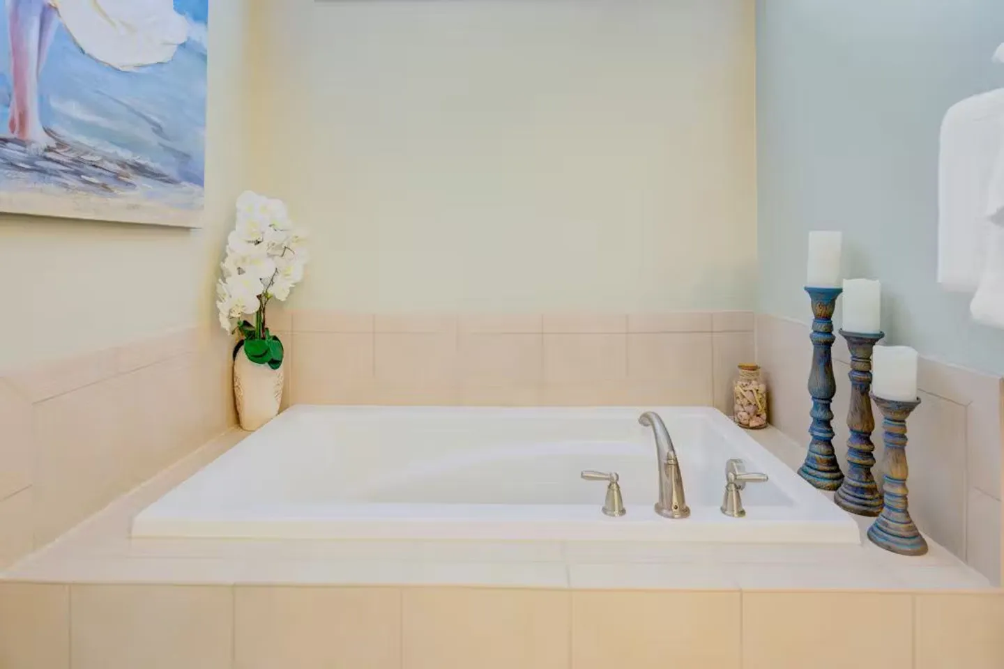 Built-in soaking tub surrounded by light-colored tile and decorative accents