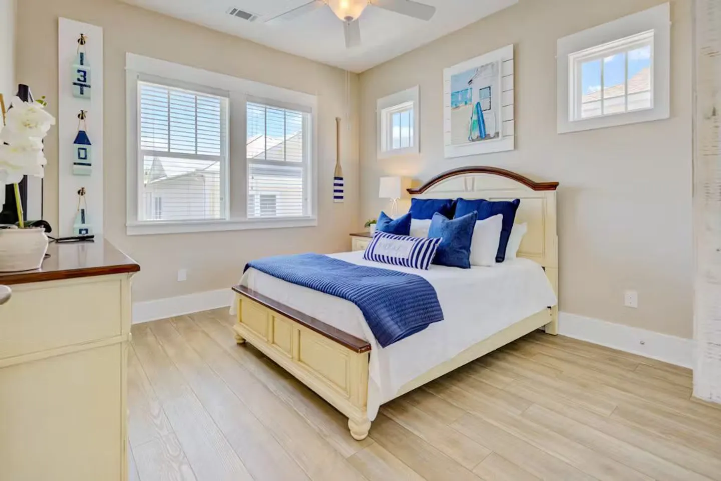Bedroom with light wood-style flooring, a bed with blue and white bedding, and coastal-themed wall decorations.
