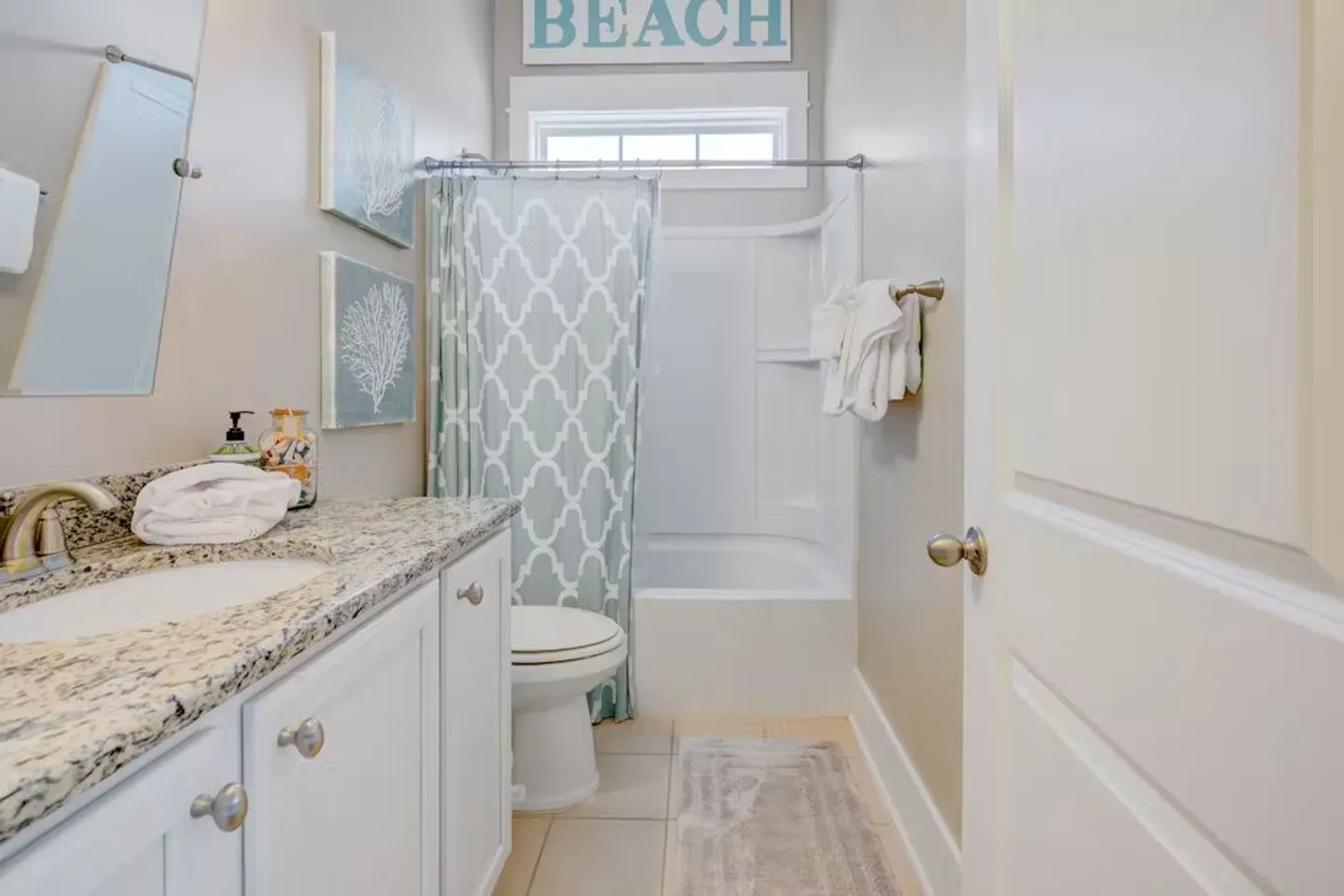 Bathroom with a granite vanity, toilet, and combination shower and bathtub behind a patterned curtain.
