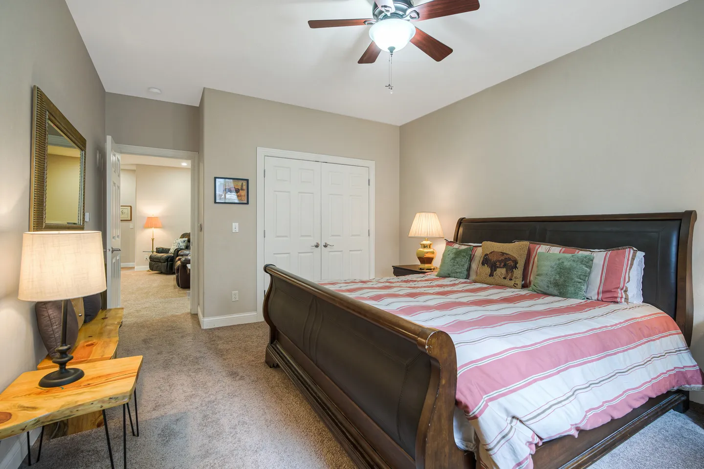 Bedroom with a wooden sleigh bed, carpeted floors, ceiling fan, and double doors to a closet.