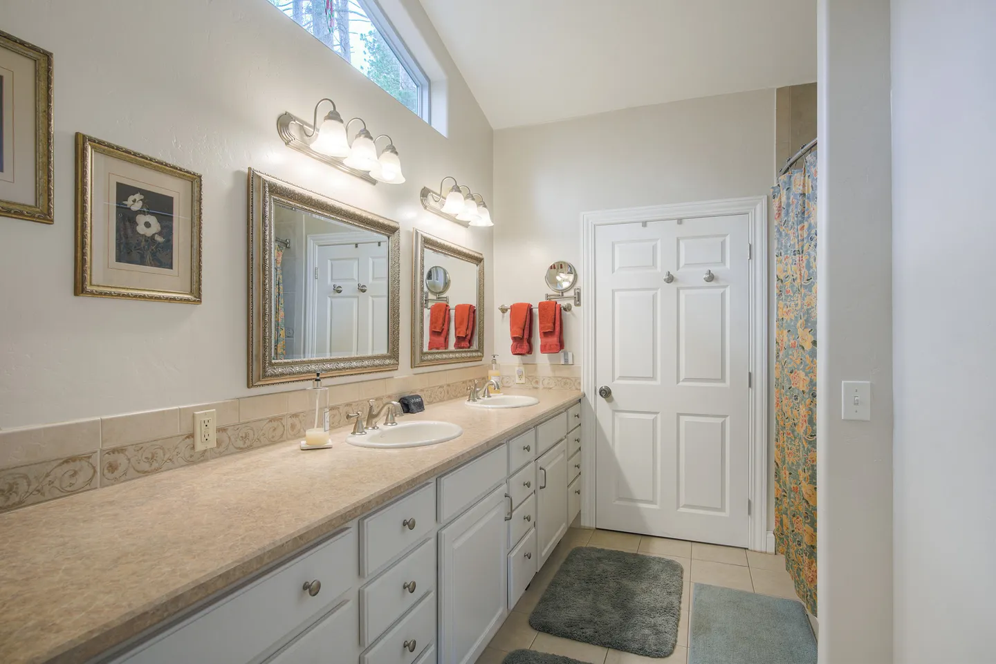 Bathroom with a double sink vanity, two framed mirrors with vanity lights, and a tiled floor.