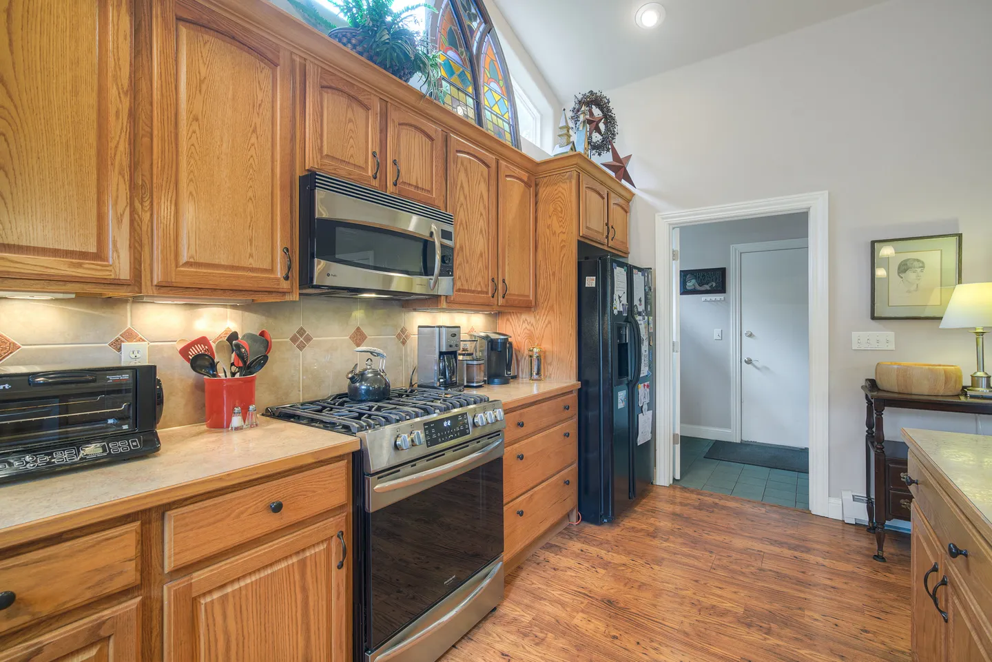 Kitchen interior featuring wood cabinetry, stainless steel oven, built-in microwave, and wood flooring.