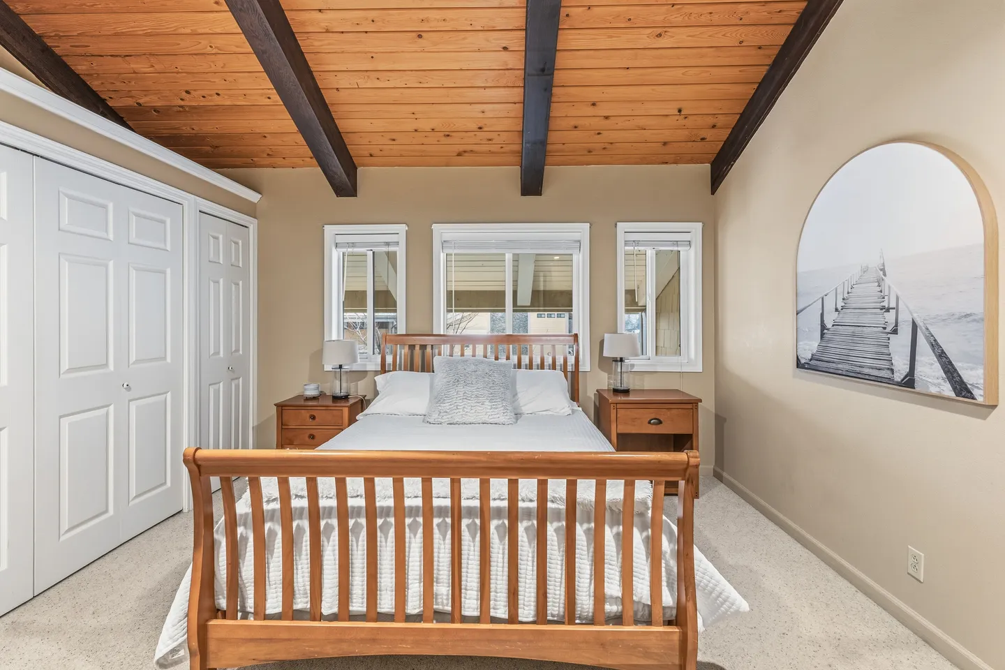 Bedroom featuring a wooden slat bed, carpeted flooring, and a vaulted wood-paneled ceiling with dark exposed beams.