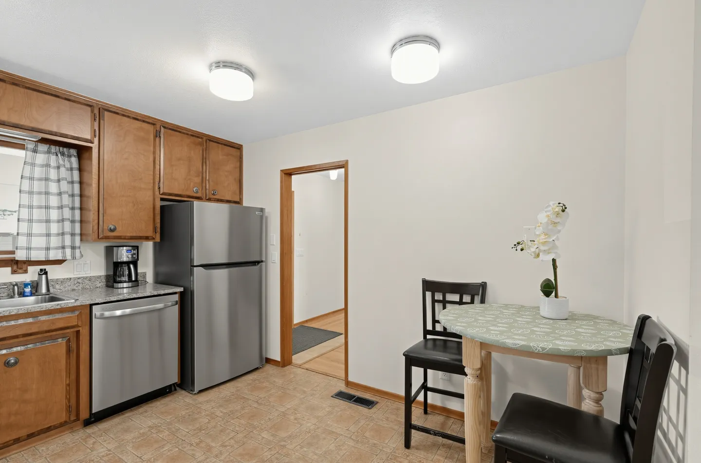Kitchen with wood cabinets, stainless steel appliances, and a small dining table with two chairs.