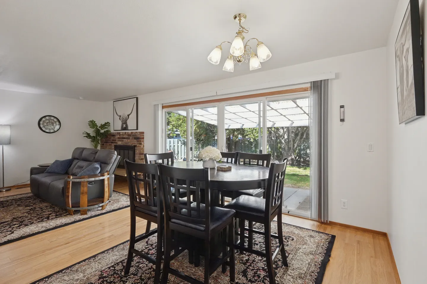 Dining area with a dark wood table and chairs over an ornate rug, next to sliding glass doors looking out to a patio.