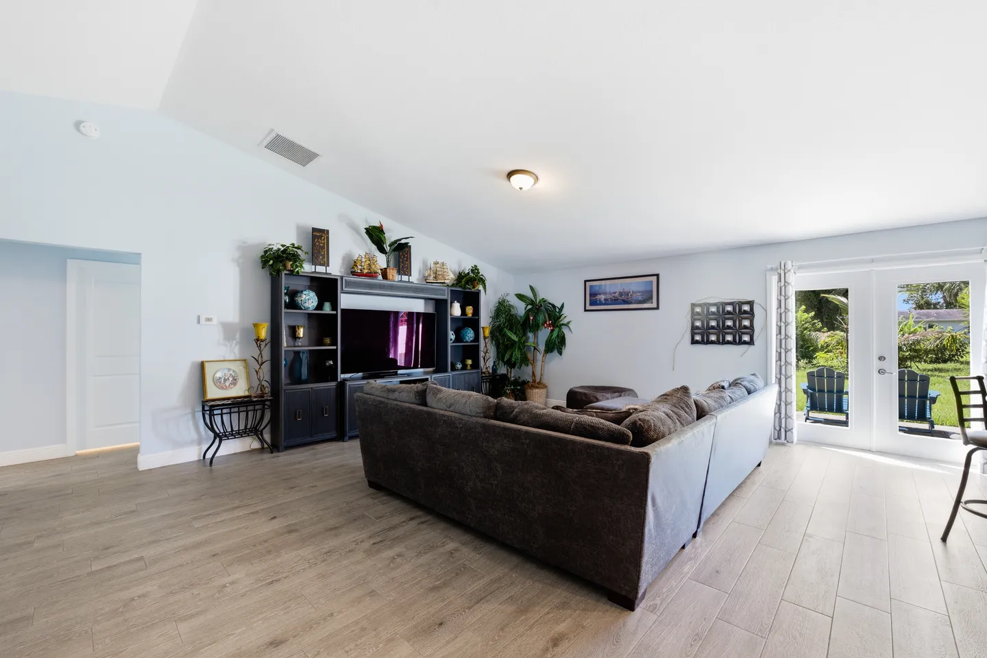 Living room with a large sectional sofa, entertainment center with TV, and glass double doors opening to the backyard.