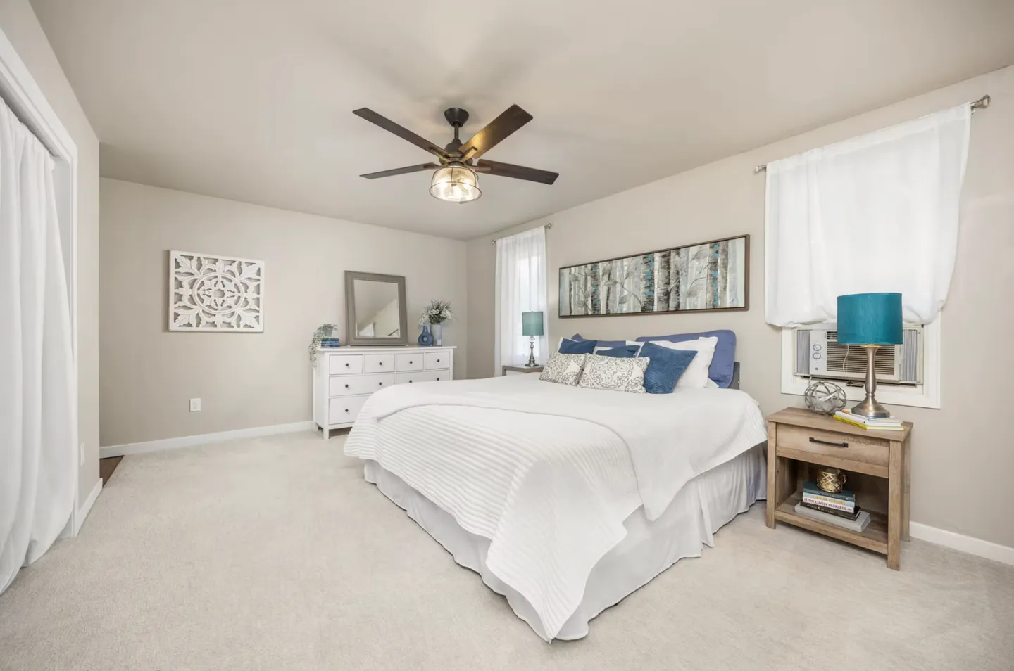 Bedroom with a made bed, carpeted floor, ceiling fan, white dresser, and nightstand.
