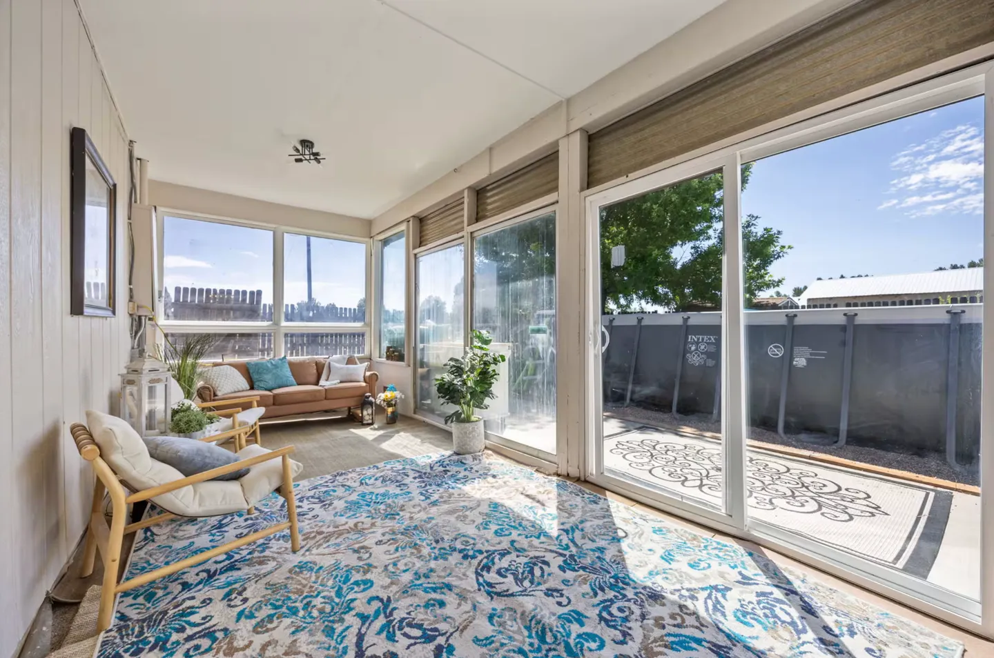 Sunroom with large glass sliding doors and windows overlooking an outdoor pool and backyard fence.