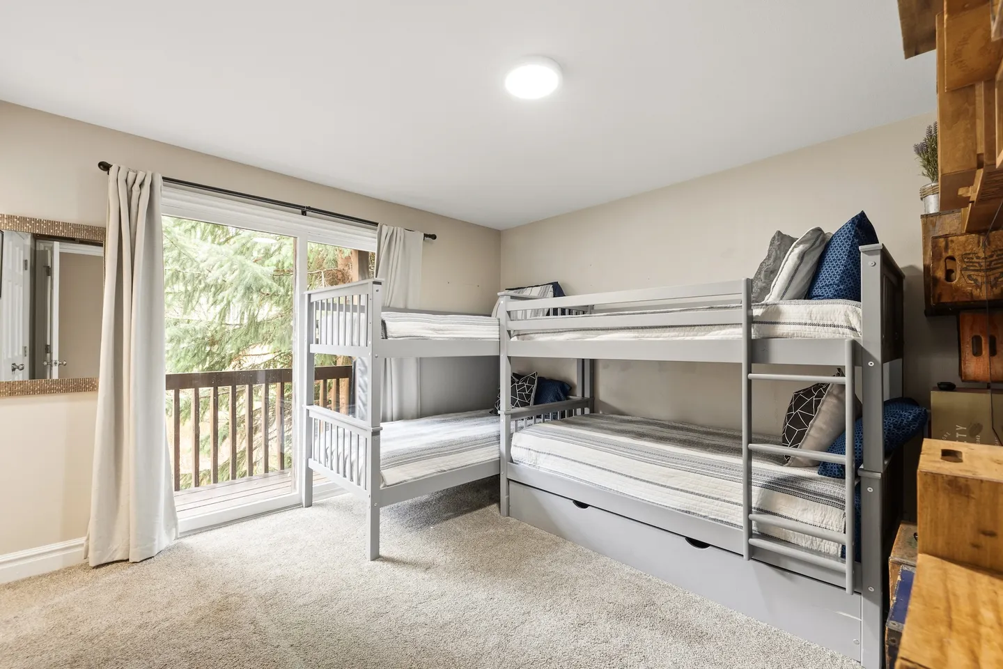 Bedroom with two connected grey bunk beds on carpet next to sliding glass doors leading to a balcony.