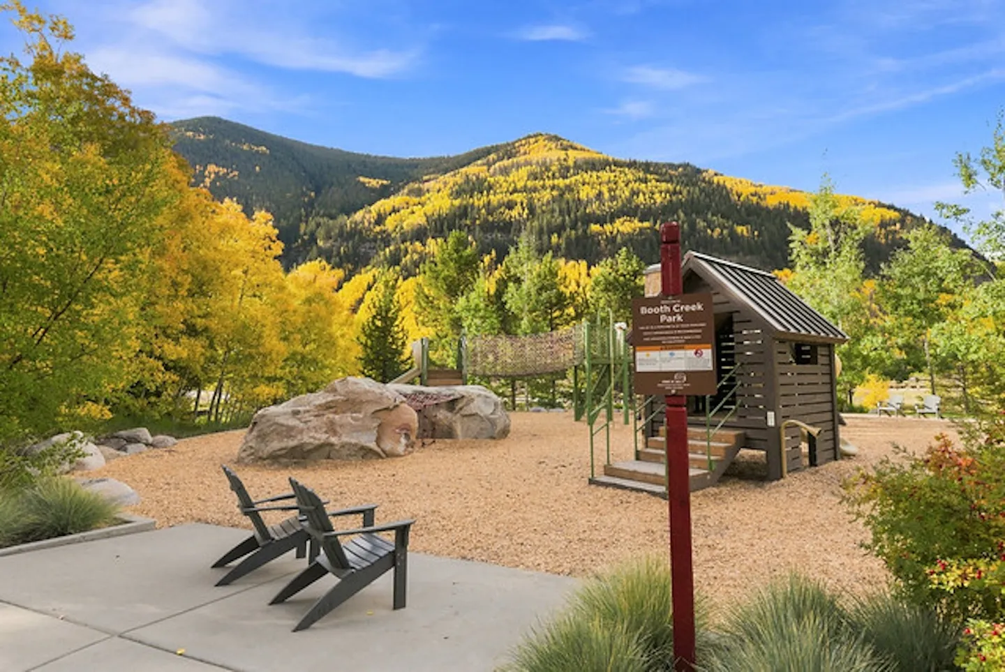 Outdoor playground at Booth Creek Park with wooden play structure and mountain backdrop filled with fall foliage.