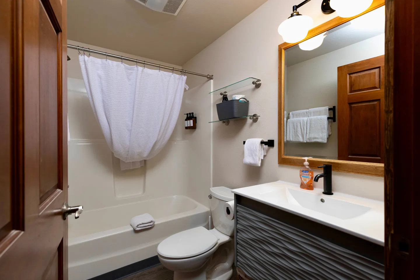 Bathroom with a modern textured vanity, toilet, and shower-tub combination with a white curtain.