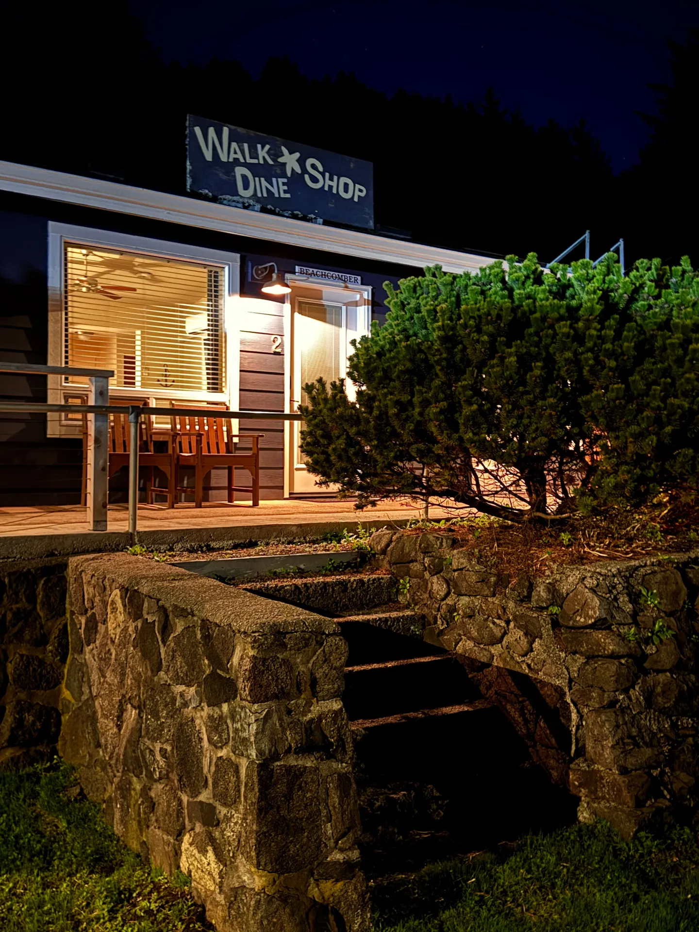 Nighttime exterior view of a cottage entrance with stone steps leading up to an illuminated porch and entry door.