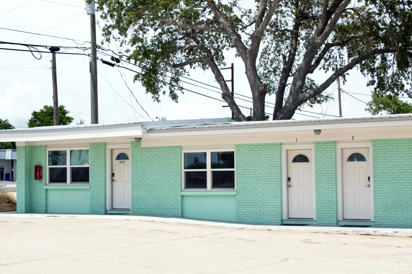 Exterior view of a single-story mint green brick building with white doors numbered 1 and 2.