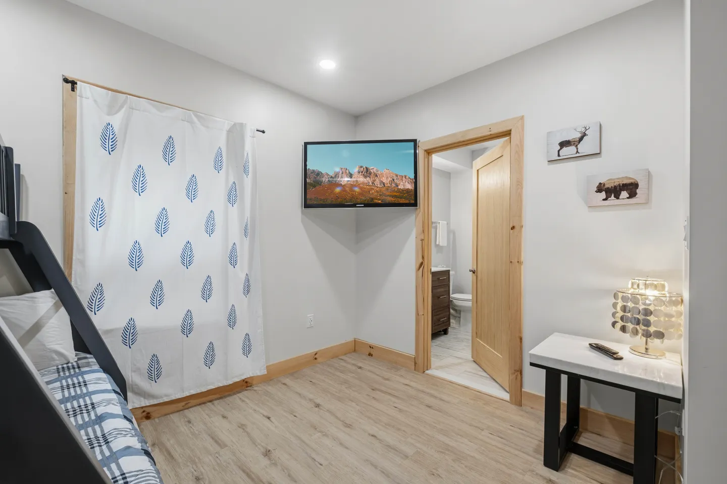 Bedroom with bunk bed, wall-mounted television, and open doorway leading to an en suite bathroom.