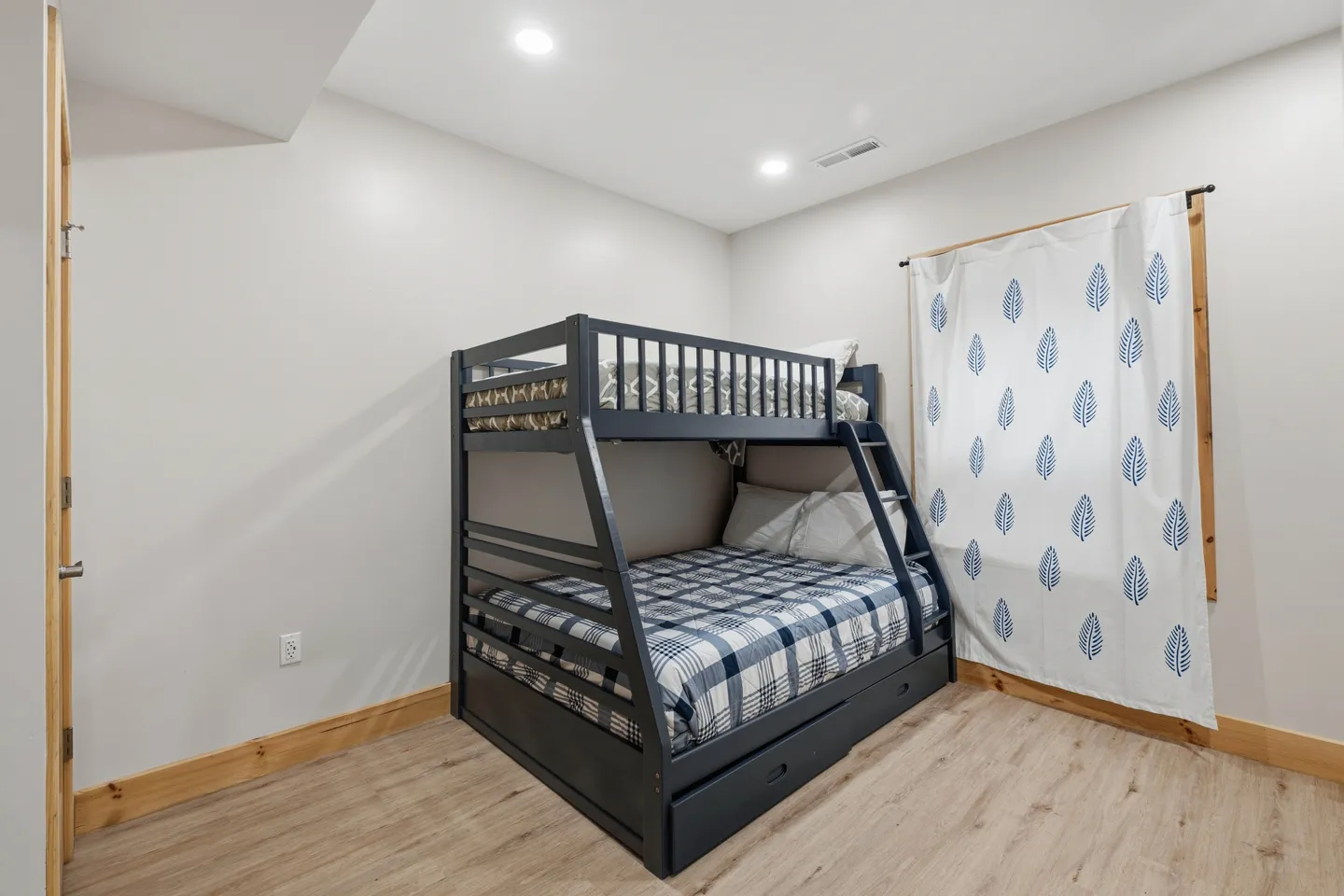 A bedroom corner featuring a dark gray bunk bed with a ladder and light-toned flooring.