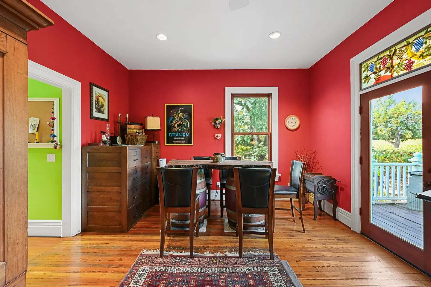 Dining room with bold red walls, hardwood floors, and a dining table supported by barrels.