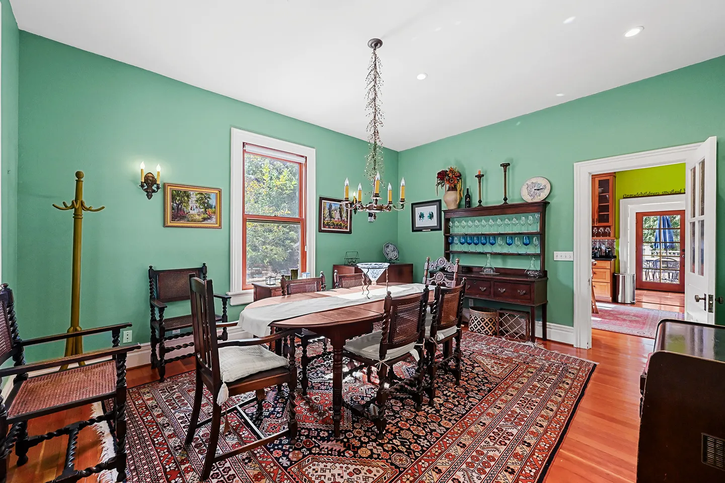 Dining room with mint green walls, wood dining table with chairs, an ornate area rug, and an open doorway leading to adjacent rooms.