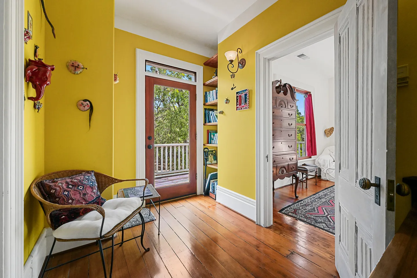 Bright yellow hallway with wood floors leading to an exterior glass door and an adjacent room.