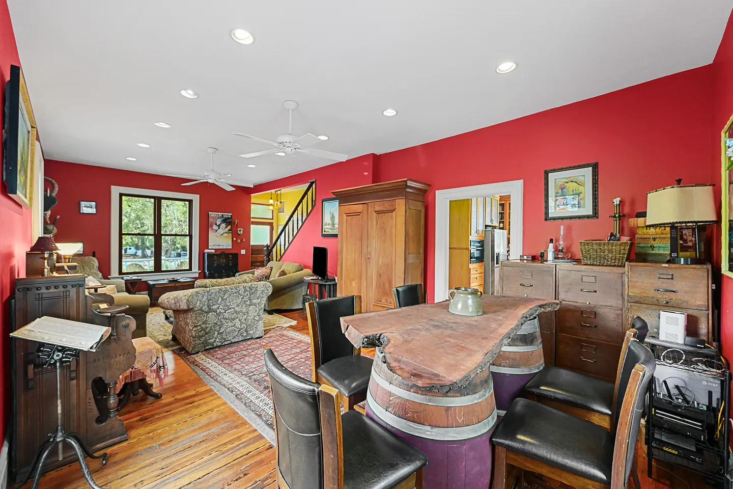 Open living and dining area with bright red walls, hardwood floors, a live-edge table supported by wine barrels, and a sitting area.