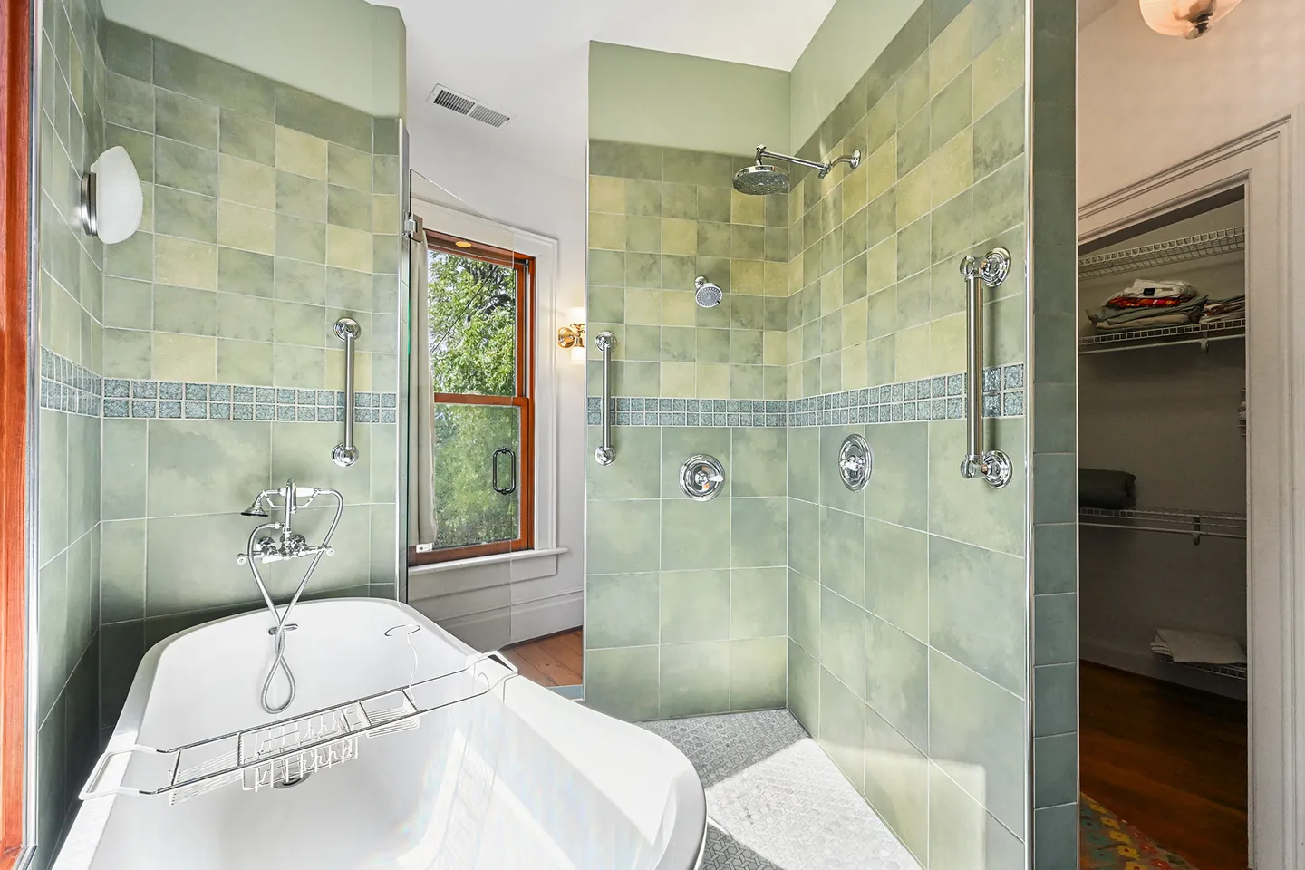 Bathroom with a standalone soaking tub and a walk-in shower lined with pale green tiles and chrome fixtures.