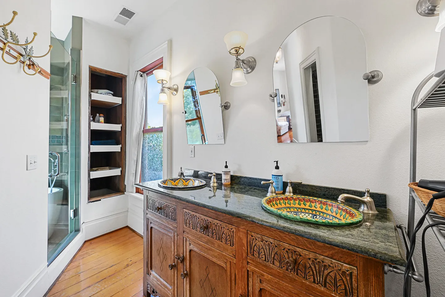 Bathroom vanity featuring an ornate wooden cabinet, two colorful hand-painted patterned vessel sinks, and mirrors.
