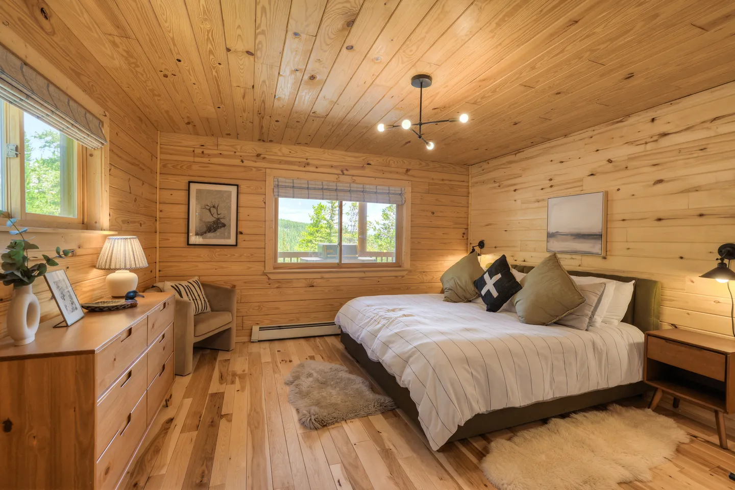 Bedroom with light wood paneled walls and ceiling, a bed with white bedding, matching wood dresser, and a window.
