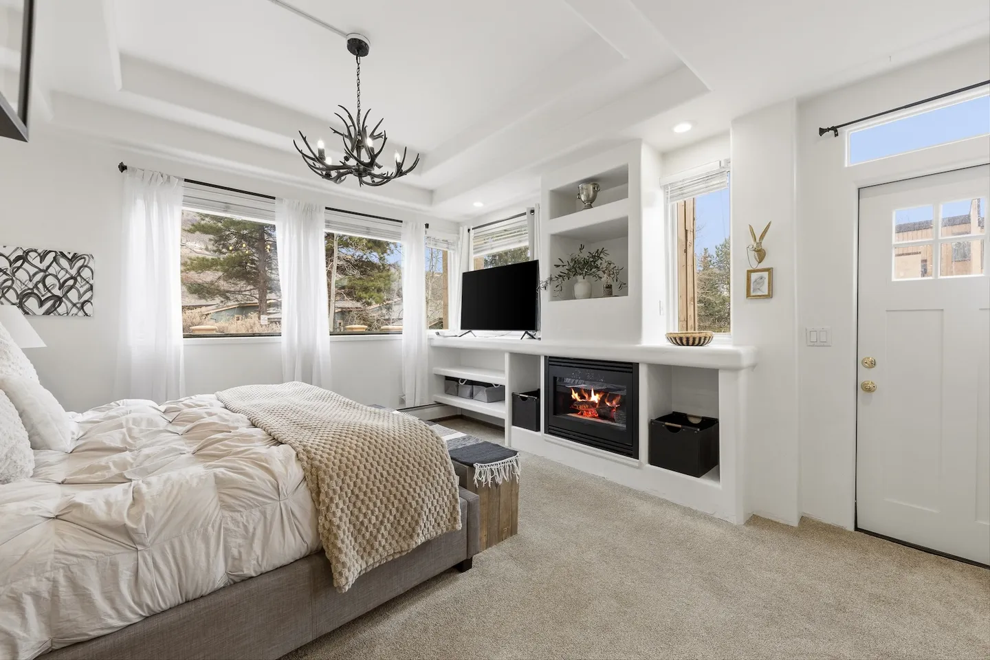 Bedroom with a bed, carpeted floor, built-in entertainment center with a fireplace and television, and an exterior door.