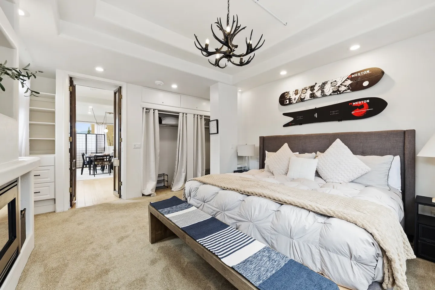 Bedroom with an upholstered bed, antler chandelier, snowboards mounted on the wall, and carpet flooring.