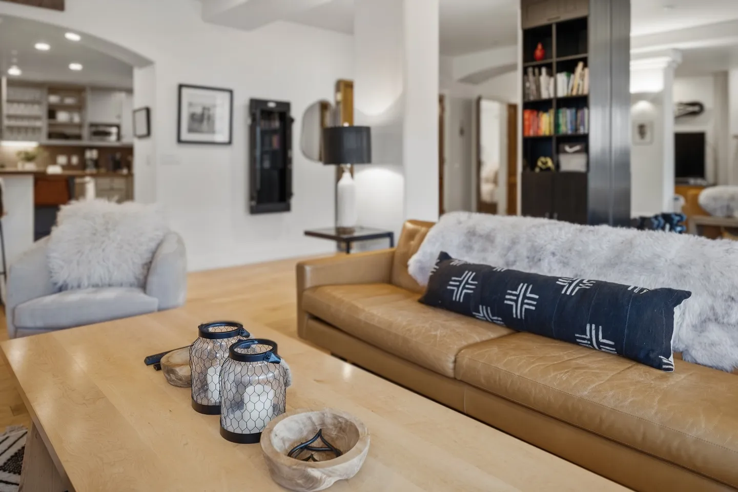 Living room featuring a light brown leather sofa, wooden coffee table, accent chair, and built-in bookshelf.