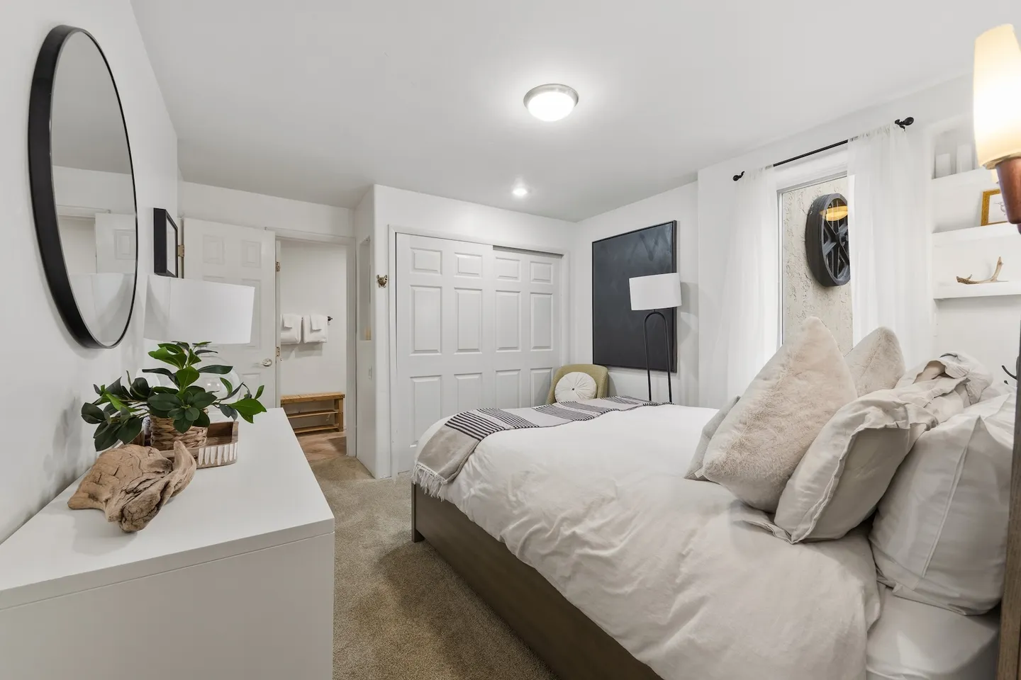 Bedroom with a made bed, carpeted floor, white dresser with mirror, and sliding closet doors.