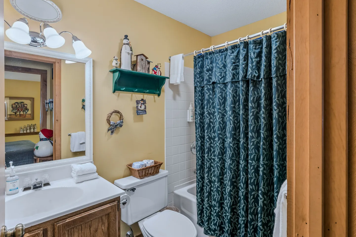Bathroom with a wood vanity, mirror, toilet, and bathtub with a patterned blue shower curtain.