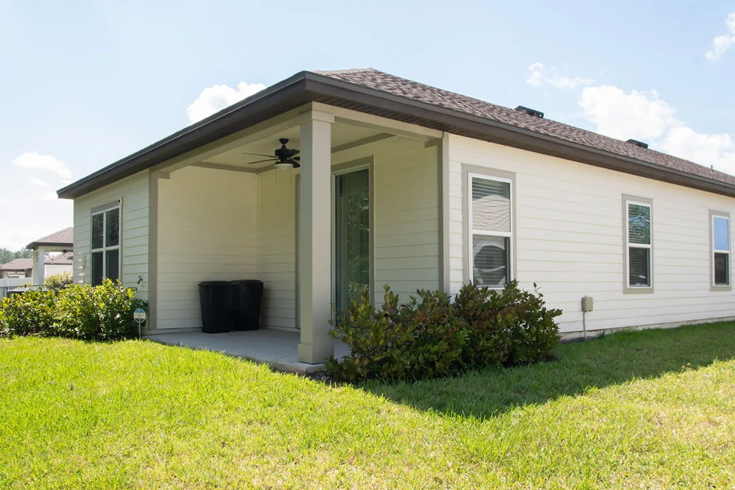 Exterior view of the back of a single-story home featuring a covered patio and grass lawn.