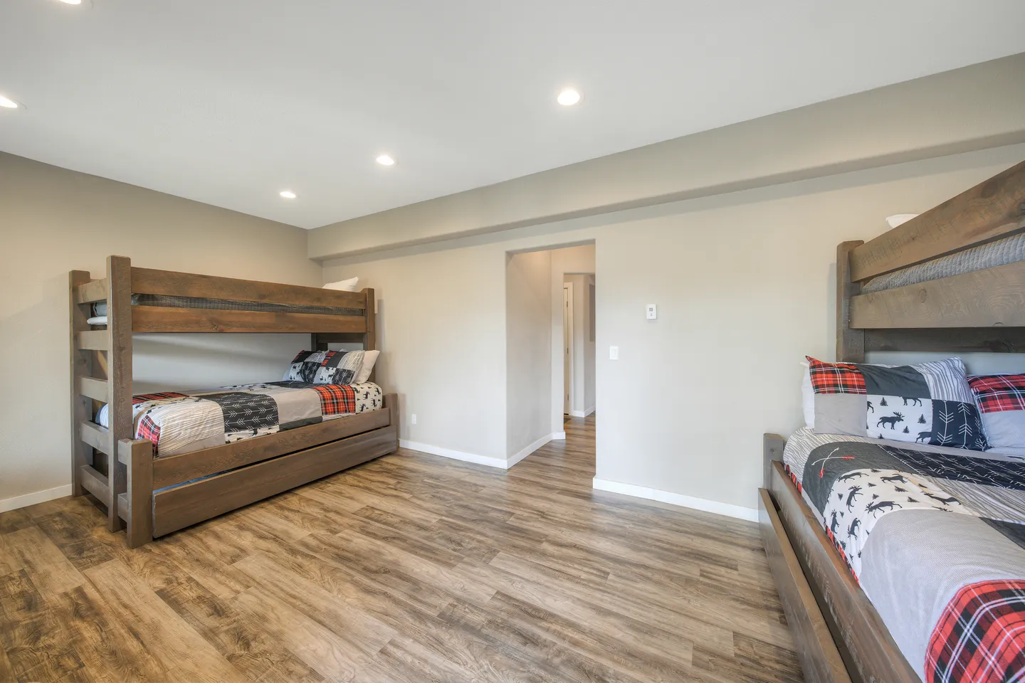 Spacious bedroom with wood-look flooring and two rustic wooden bunk bed sets.