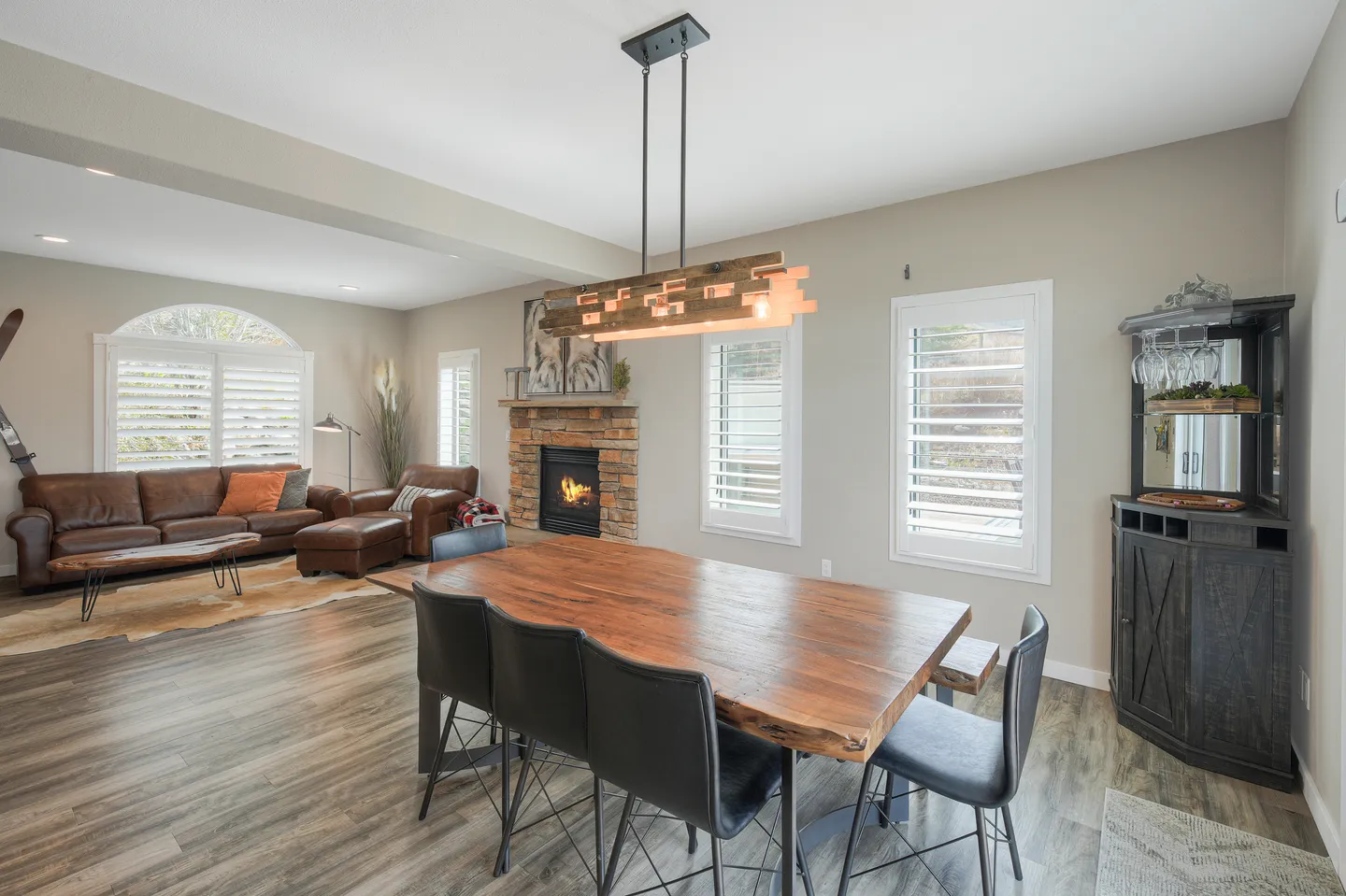 Open dining area with a live-edge wooden table leading into a living room with a stone fireplace.
