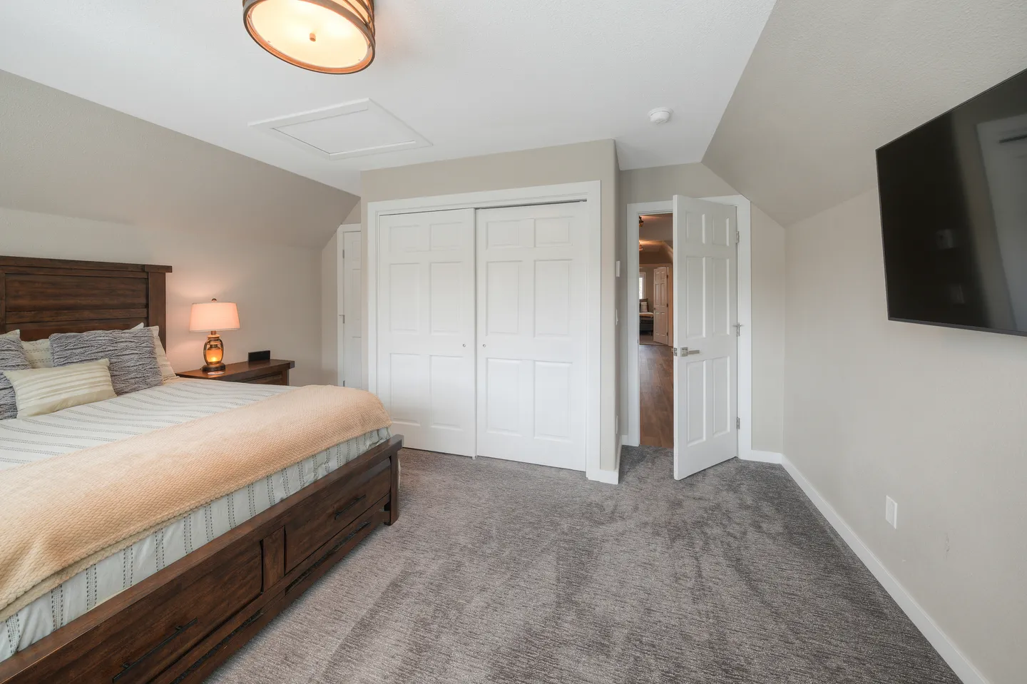 Bedroom featuring a wooden bed, carpeted floors, sliding closet doors, and an open doorway leading to a hallway.