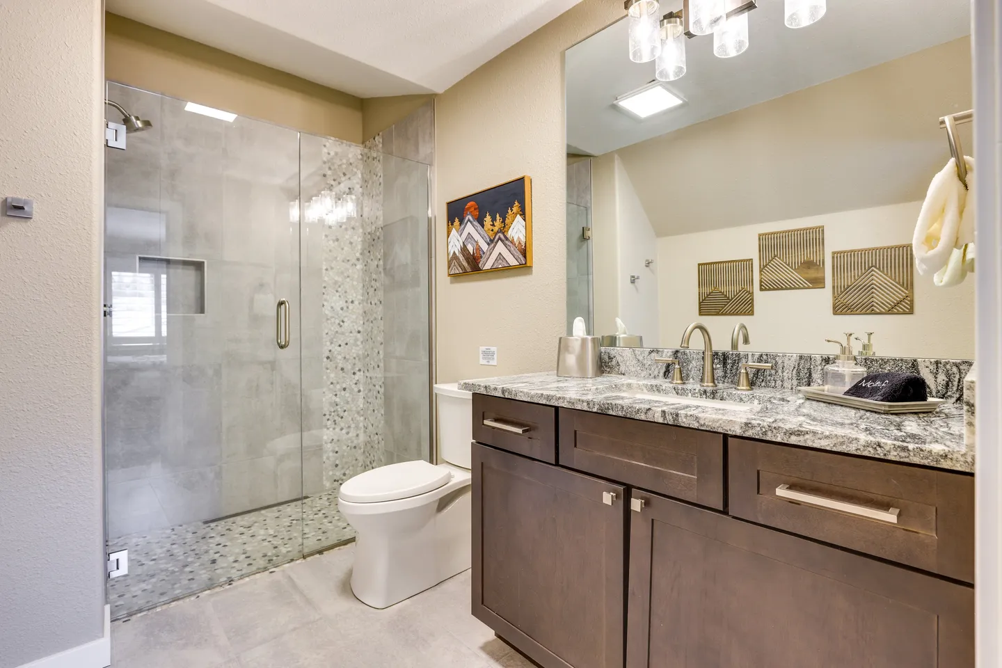 Bathroom featuring a dark wood vanity with a stone countertop, a toilet, and a glass-enclosed walk-in shower with gray tile.