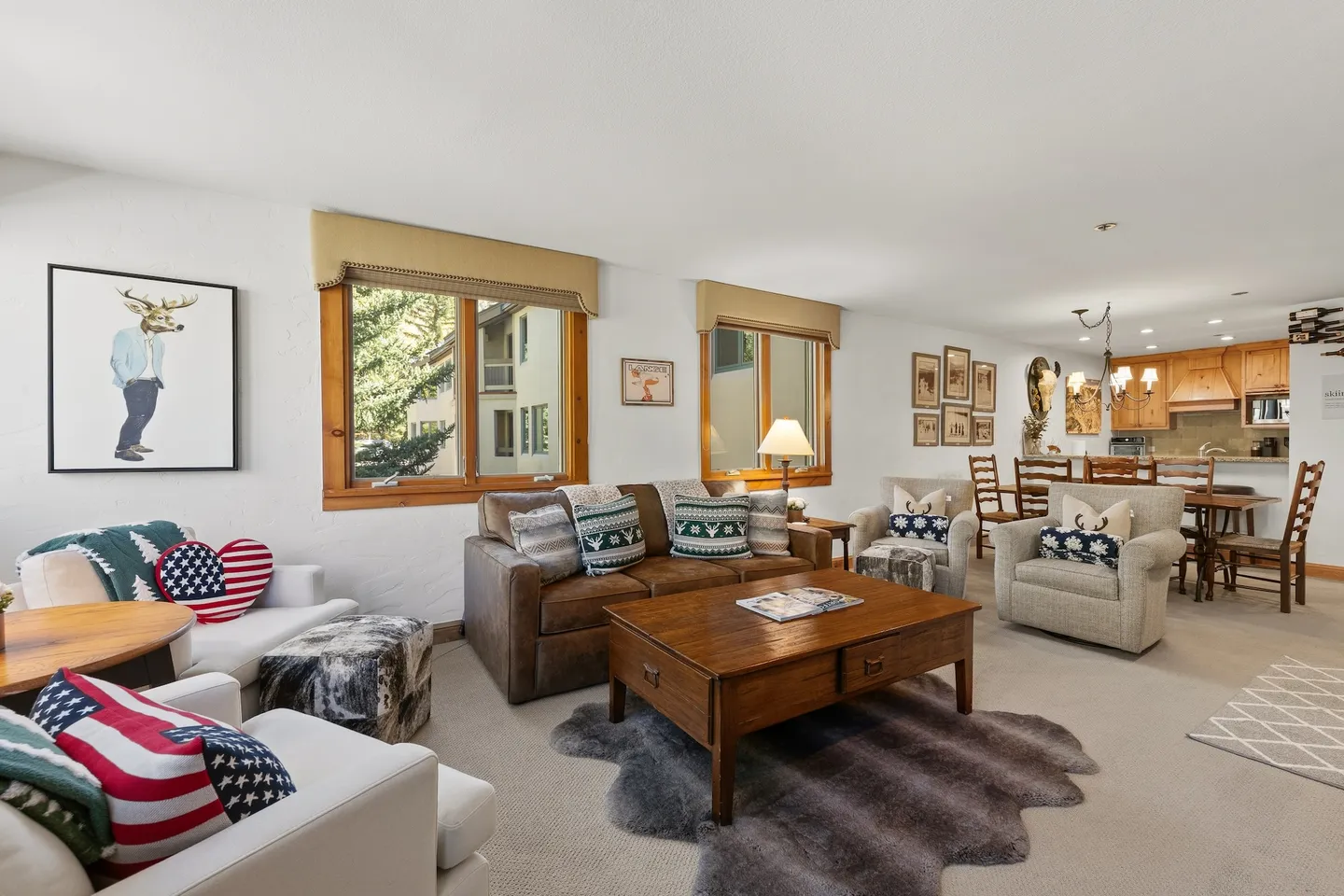 Open-concept living room featuring a leather sofa, armchairs, wooden coffee table, and an adjacent dining area leading to the kitchen.