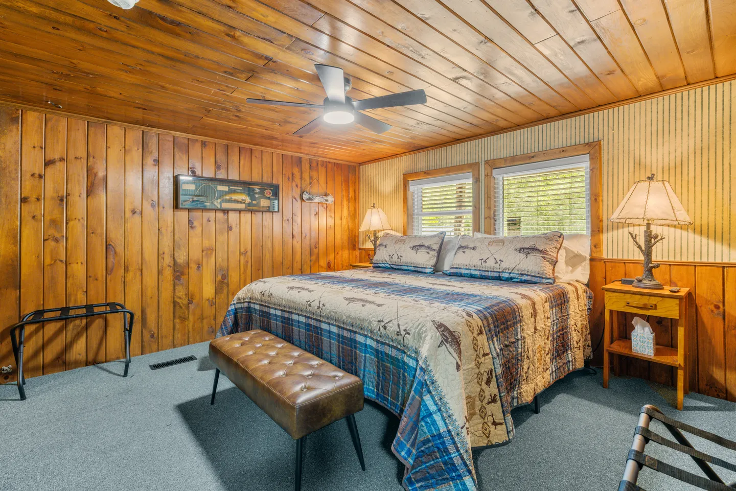 Bedroom with wood-paneled walls and ceiling, a large bed with fish-patterned bedding, and carpeted flooring.
