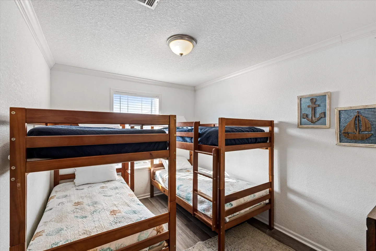Bunk bedroom with two wooden bunk beds and nautical wall art.