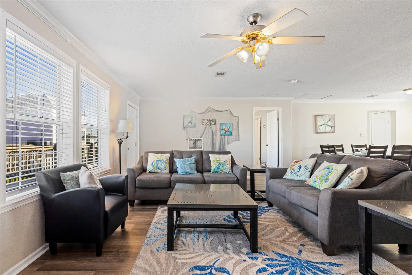 Living room with two gray sofas, a dark armchair, coffee table, and area rug beneath a ceiling fan.