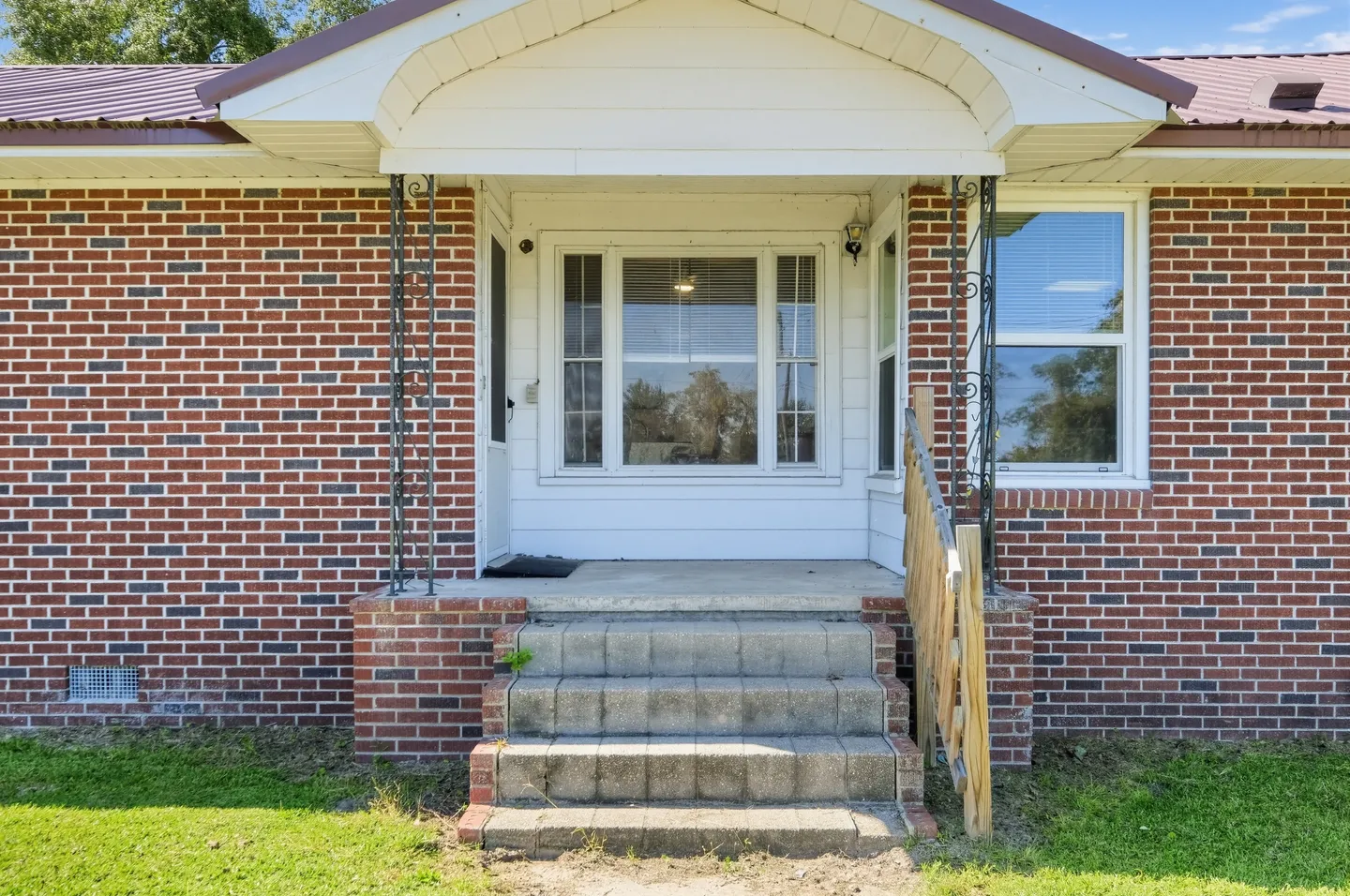 Front porch and concrete steps leading to the entrance of a red brick house.