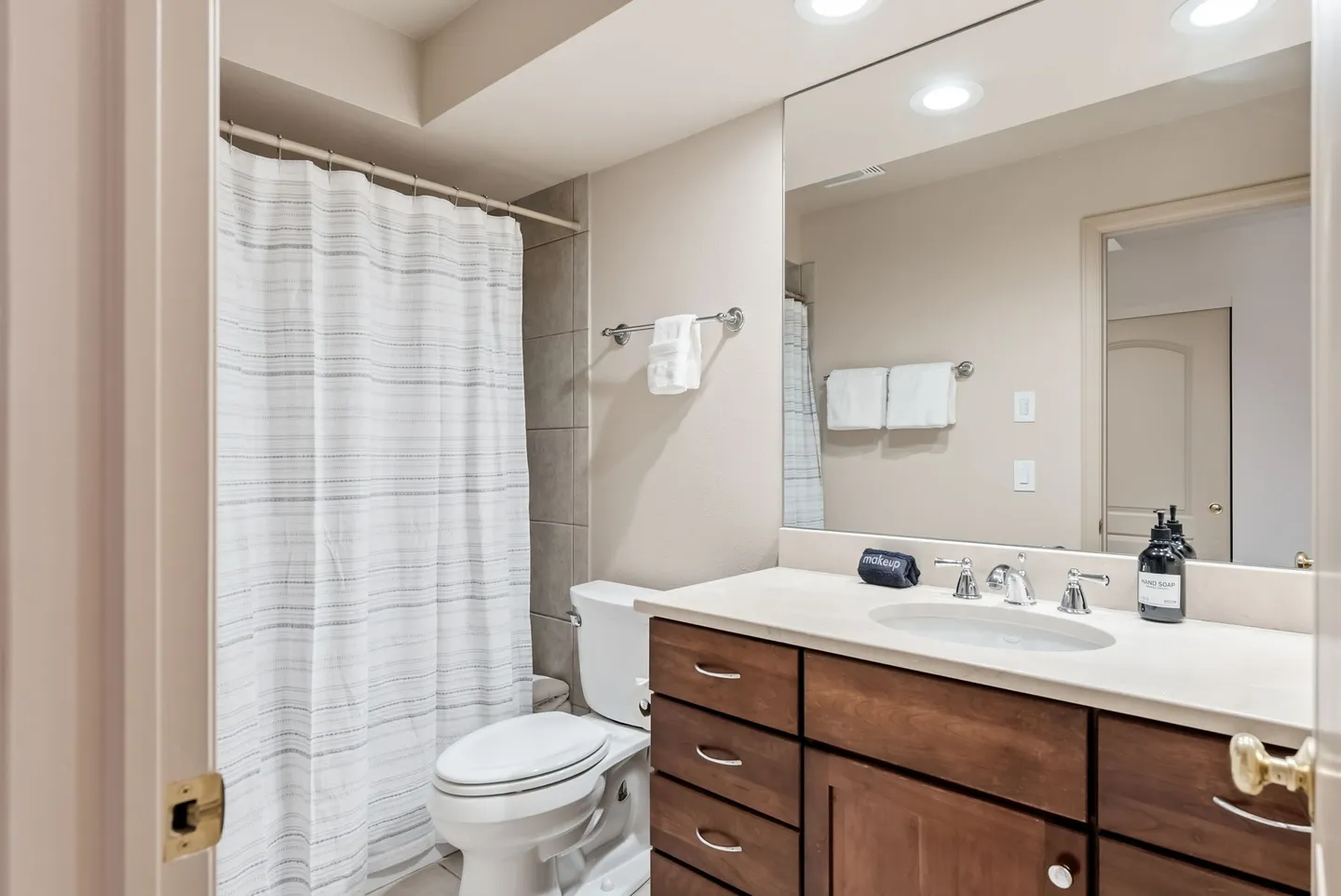 Bathroom with a dark wood vanity, white countertop, toilet, and shower curtain.