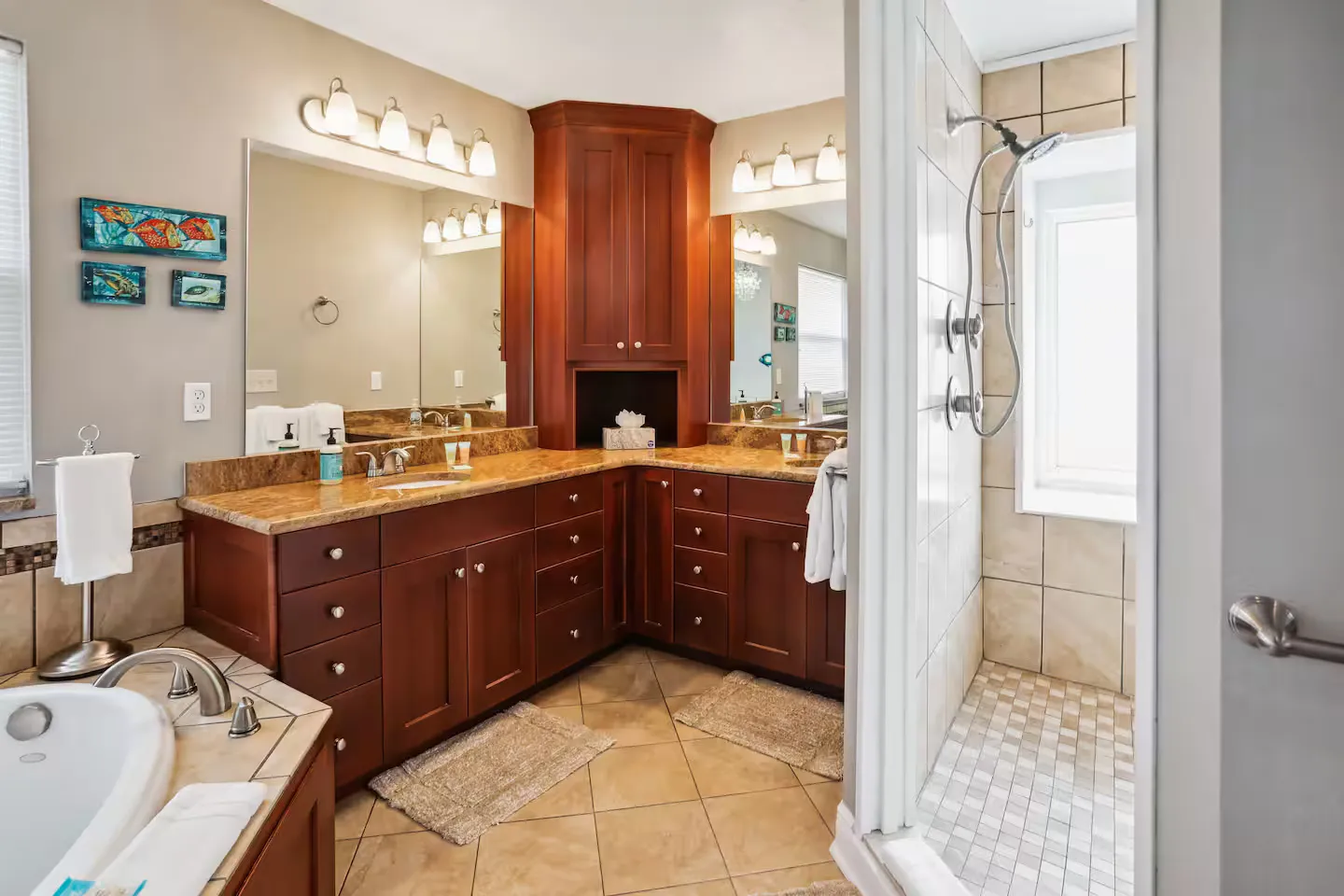 Bathroom with corner wood vanity, double mirrors, a tiled walk-in shower, and a built-in tub.