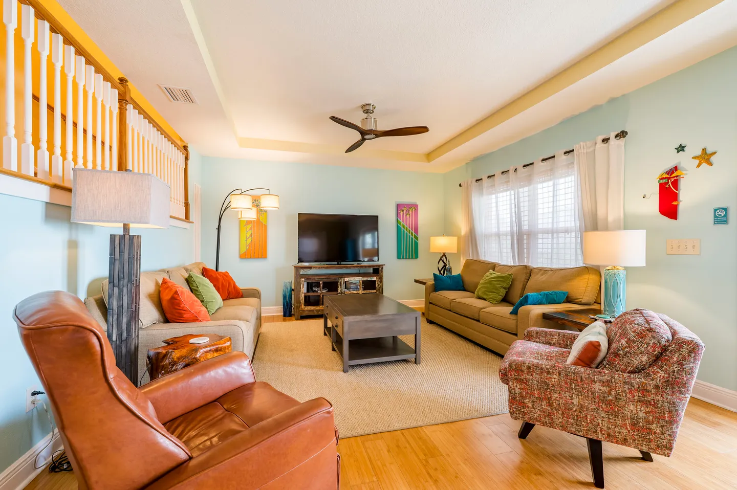 Living room with light blue walls, two beige sofas, an armchair, a leather recliner, a coffee table, and a wall-mounted TV.