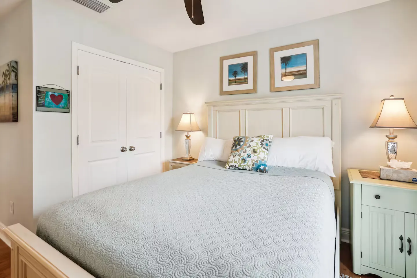 Bedroom featuring a made bed with an off-white headboard, flanked by nightstands with table lamps.
