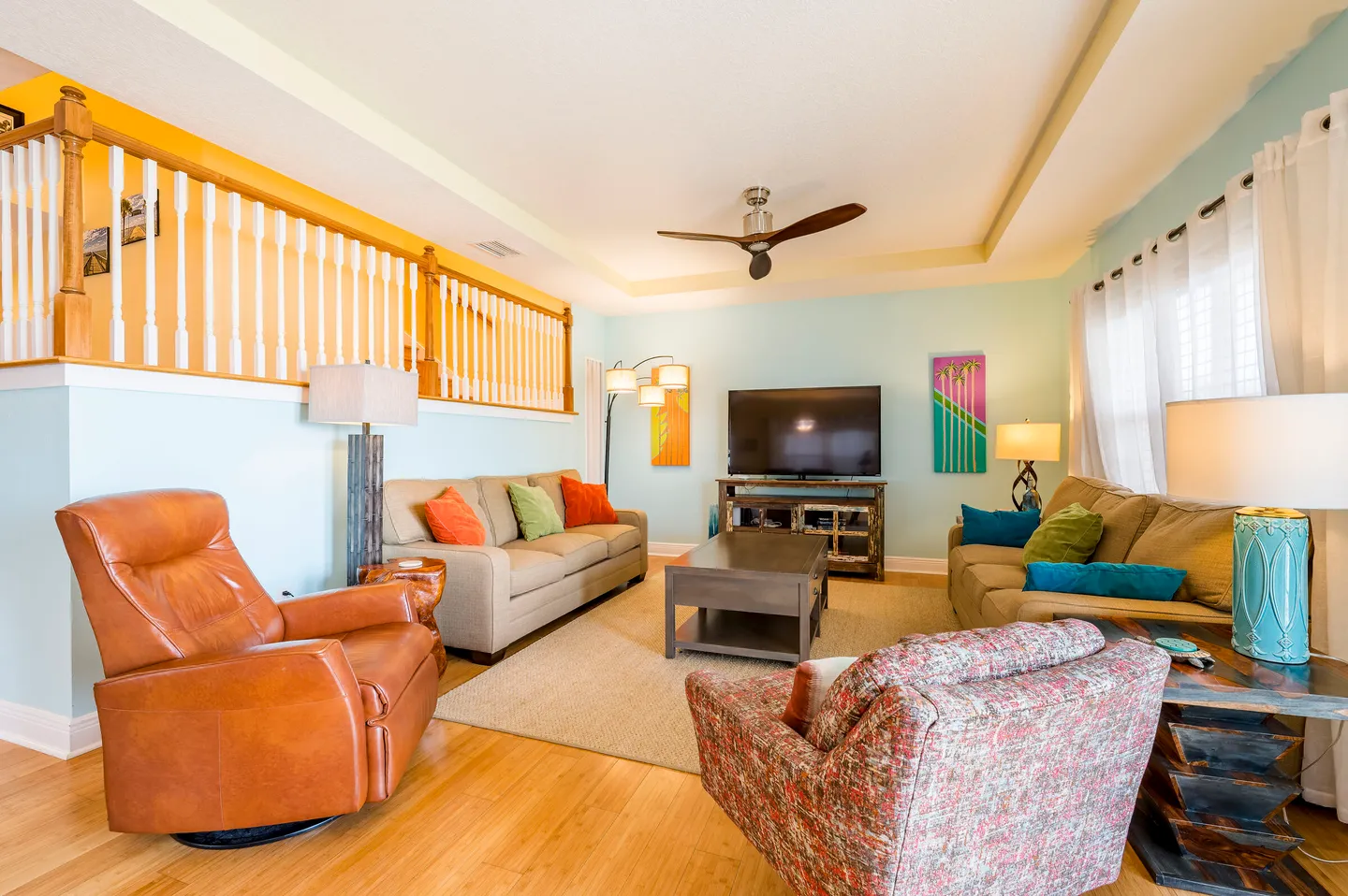 Bright living room with two sofas, an armchair, a leather recliner, a coffee table, and a flat-screen TV.